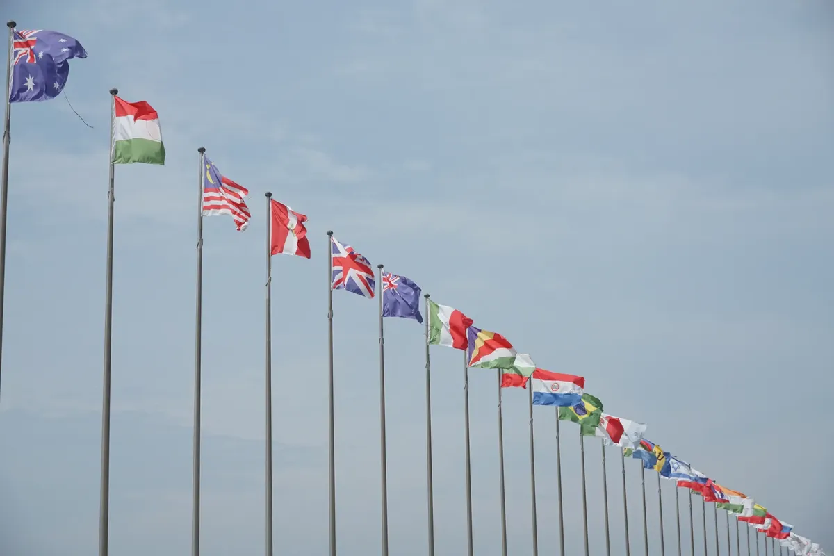 A row of international flags on flagpoles symbolizing global unity and diplomacy.
