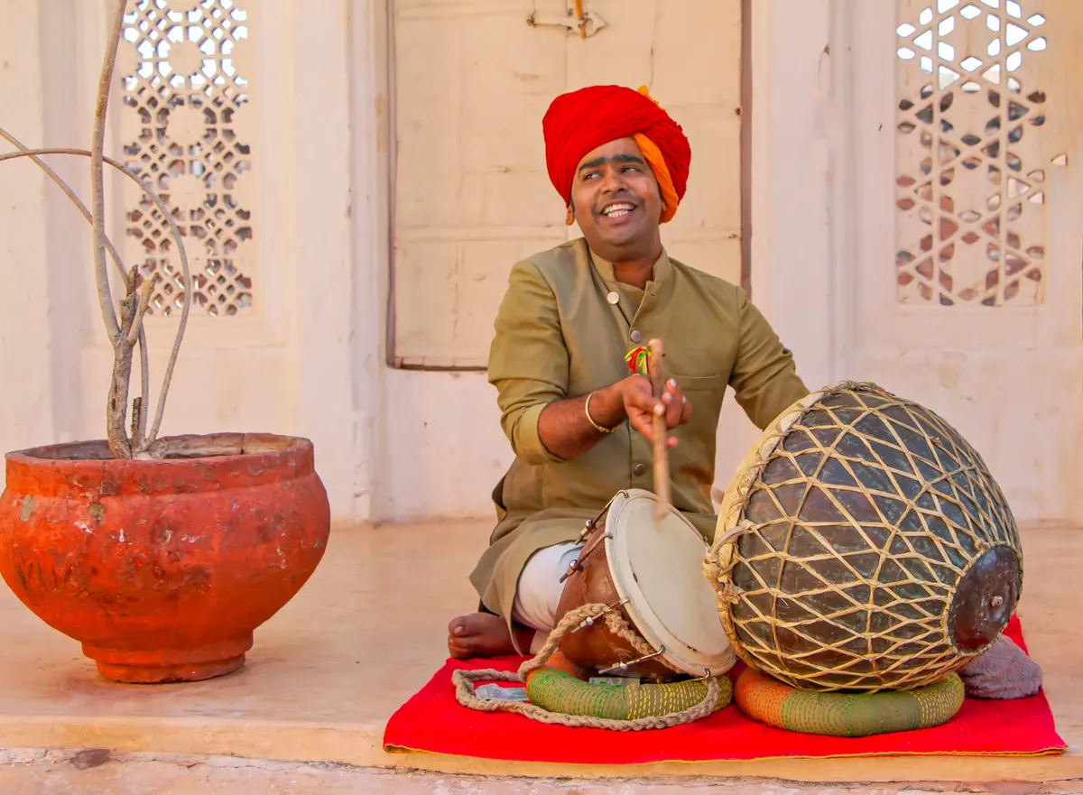 South Asian man performing traditional music with drum in Udaipur, India.