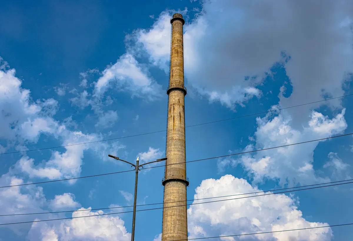 A towering chimney set against a blue sky with clouds, showcasing industrial architecture in Delhi, India.
