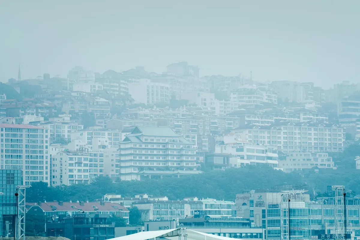 A hazy cityscape showing multiple buildings under smog and fog, highlighting urban air pollution.