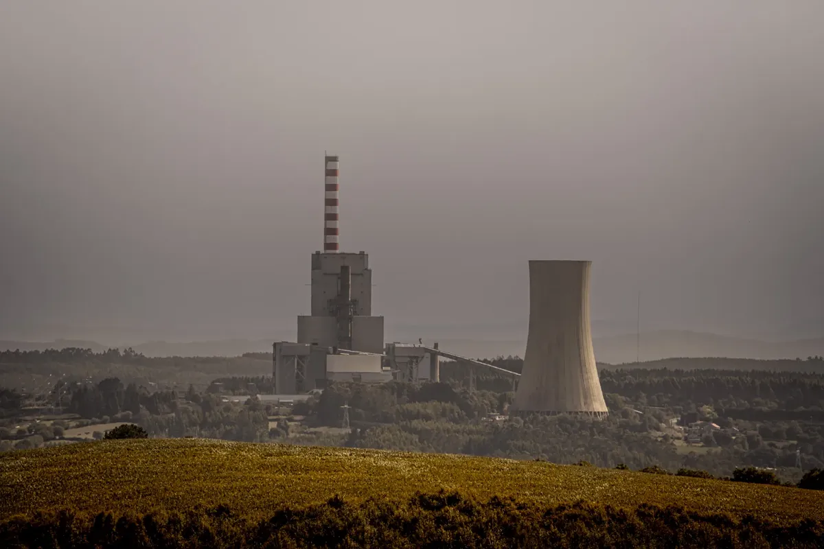 A coal-fired power plant emits smoke on an overcast day, highlighting energy and environmental issues.