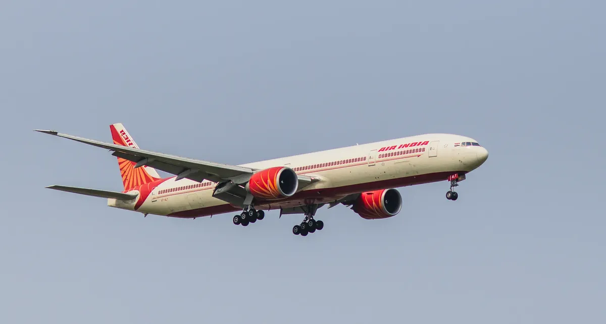 Air India Boeing 777 aircraft captured mid-flight against a clear blue sky, showcasing its design and logo.